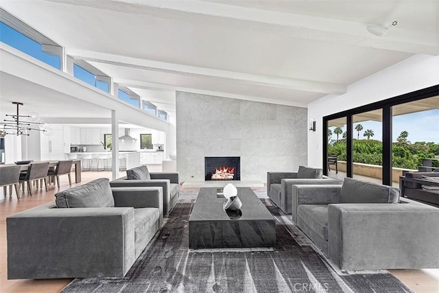 living area with a chandelier, a fireplace, wood finished floors, and beam ceiling