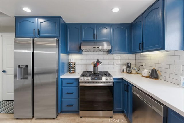 kitchen with appliances with stainless steel finishes, light countertops, under cabinet range hood, and blue cabinetry