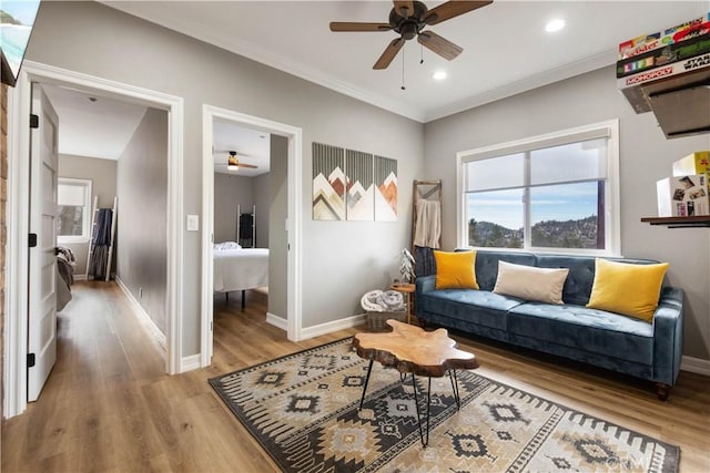 living room featuring baseboards, ornamental molding, wood finished floors, and recessed lighting