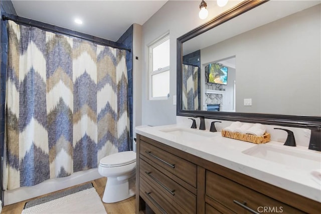 bathroom featuring toilet, shower / tub combo, wood finished floors, and vanity