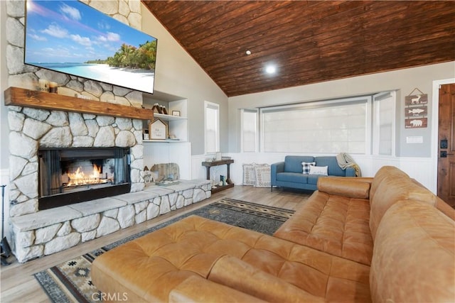 living area featuring wainscoting, wooden ceiling, wood finished floors, a fireplace, and high vaulted ceiling