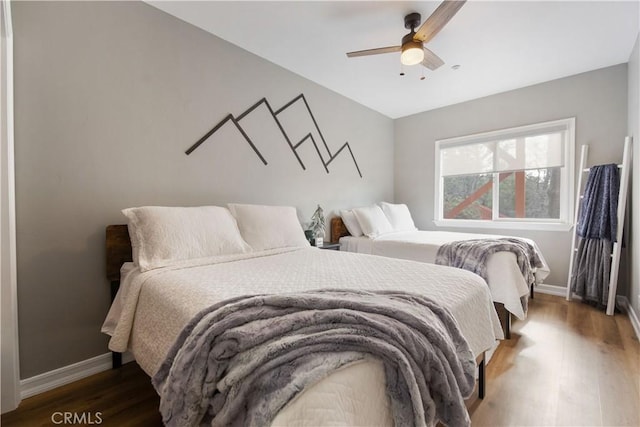 bedroom featuring wood finished floors, a ceiling fan, and baseboards