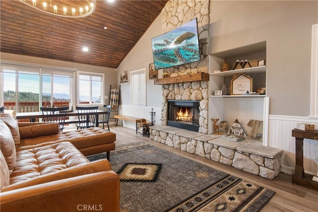 living room featuring wooden ceiling, wainscoting, a stone fireplace, and wood finished floors