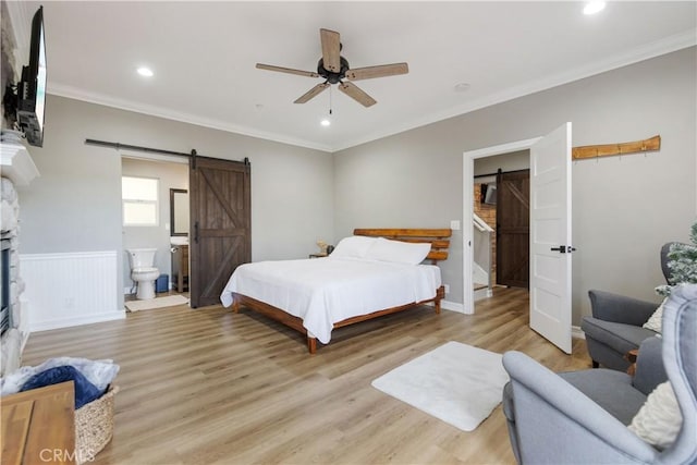 bedroom with a barn door, connected bathroom, crown molding, light wood-type flooring, and recessed lighting