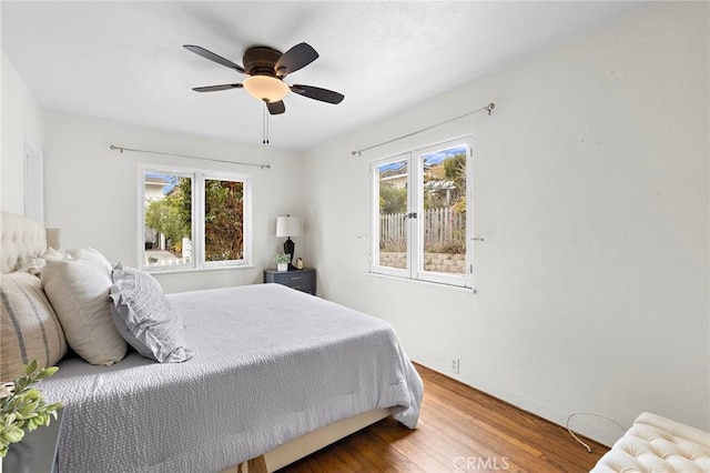 bedroom with ceiling fan, multiple windows, and wood finished floors