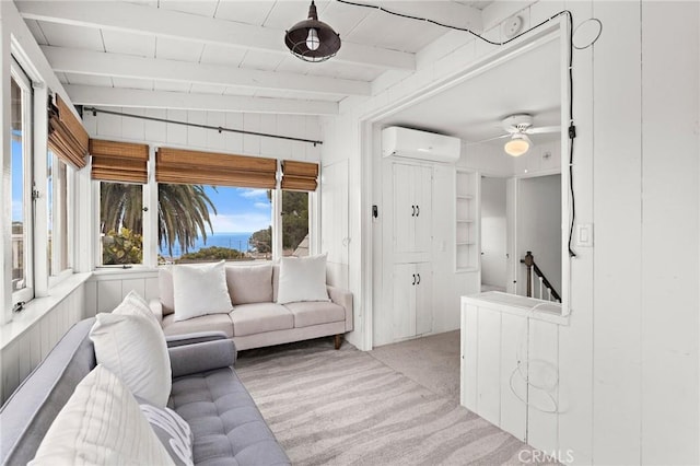 living area featuring wooden walls, light carpet, a ceiling fan, a wall mounted AC, and beamed ceiling