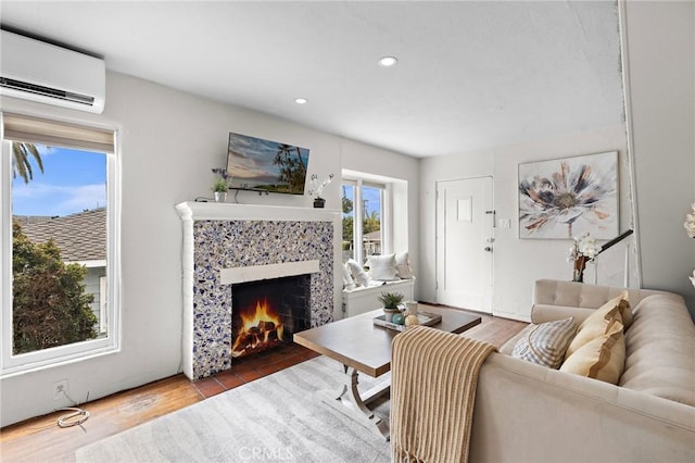 living area featuring a tiled fireplace, a wall mounted air conditioner, wood finished floors, and recessed lighting