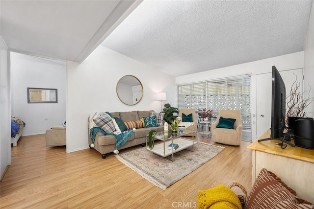 living room featuring light wood-type flooring, baseboards, and a textured ceiling