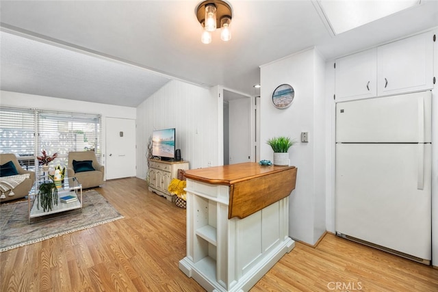 kitchen with light wood-style flooring, open floor plan, freestanding refrigerator, white cabinetry, and open shelves