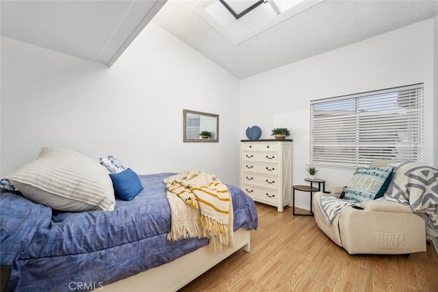 bedroom with lofted ceiling with skylight and light wood-style flooring