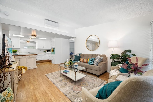 living area with light wood finished floors, a textured ceiling, and a wall mounted AC