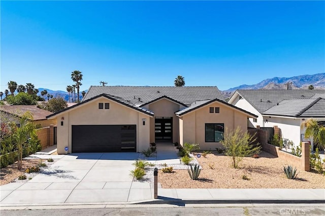 view of front of property with a garage, fence, a mountain view, and stucco siding