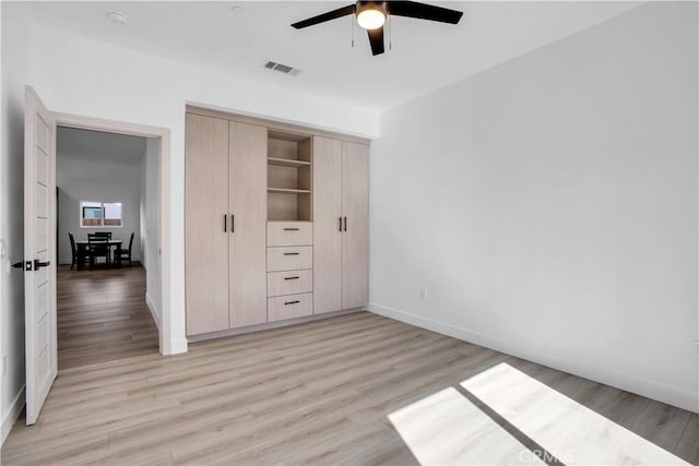 unfurnished bedroom with light wood finished floors, baseboards, visible vents, a ceiling fan, and a closet