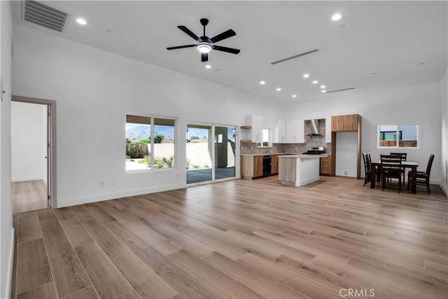 unfurnished living room featuring recessed lighting, visible vents, a towering ceiling, light wood-style floors, and ceiling fan