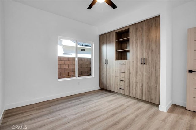 unfurnished bedroom with ceiling fan, light wood-style flooring, and baseboards