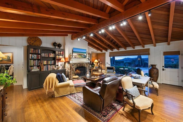 living room featuring lofted ceiling with beams, a fireplace, wood finished floors, and wooden ceiling