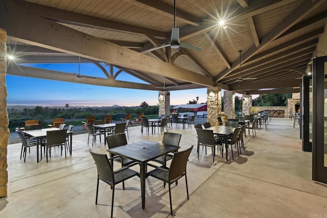 patio terrace at dusk featuring ceiling fan, outdoor dining area, and a gazebo