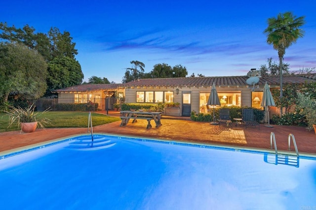 pool at dusk with a patio, fence, and a fenced in pool