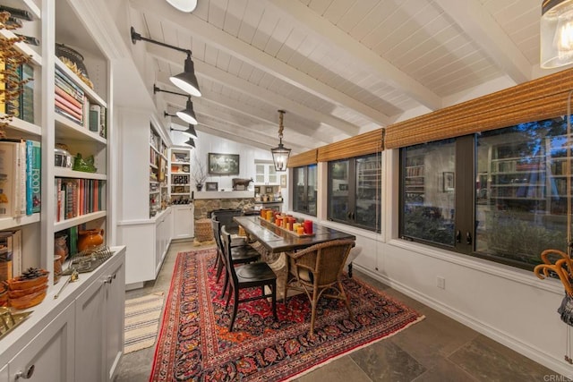 dining room featuring lofted ceiling with beams, wooden ceiling, a fireplace, and baseboards