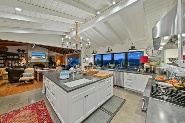 kitchen with lofted ceiling with beams, open floor plan, dishwasher, a lit fireplace, and wall chimney exhaust hood