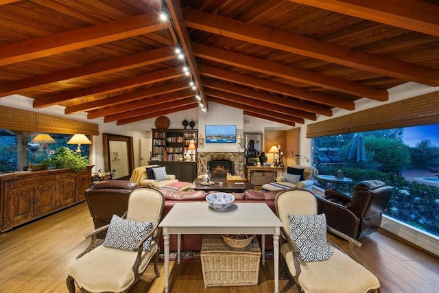 interior space featuring vaulted ceiling with beams, wood ceiling, a fireplace, and light wood-style flooring