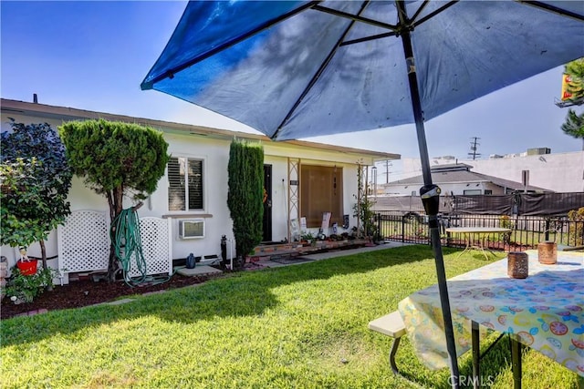 exterior space with a lawn, fence, and stucco siding