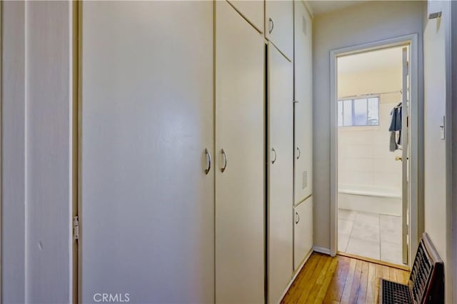 hall featuring light wood-style flooring and visible vents
