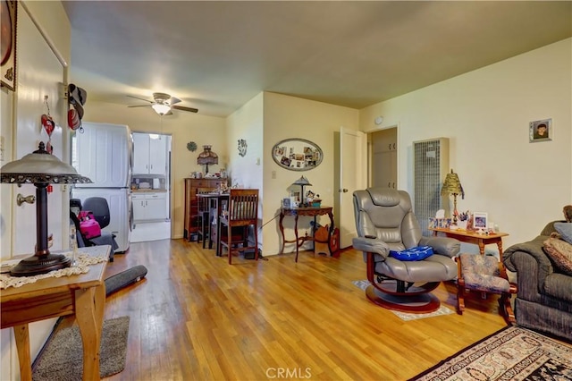 living area featuring a heating unit, ceiling fan, and wood finished floors