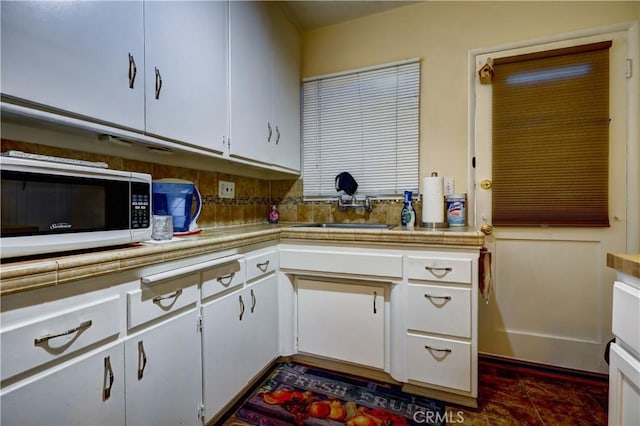kitchen with light countertops, white cabinets, and a sink