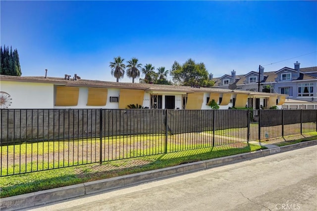 view of front of property with a residential view, a fenced front yard, a front lawn, and stucco siding