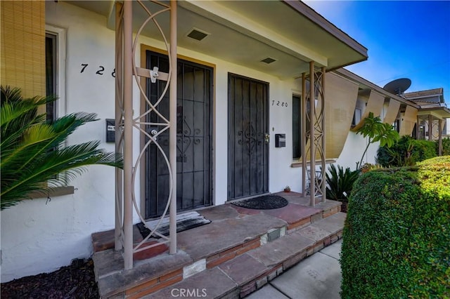 entrance to property with stucco siding and covered porch