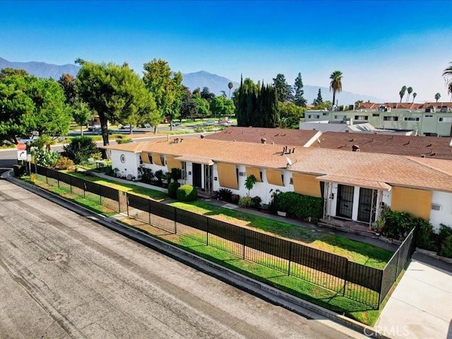 ranch-style house with a front lawn, a fenced front yard, a residential view, and a mountain view