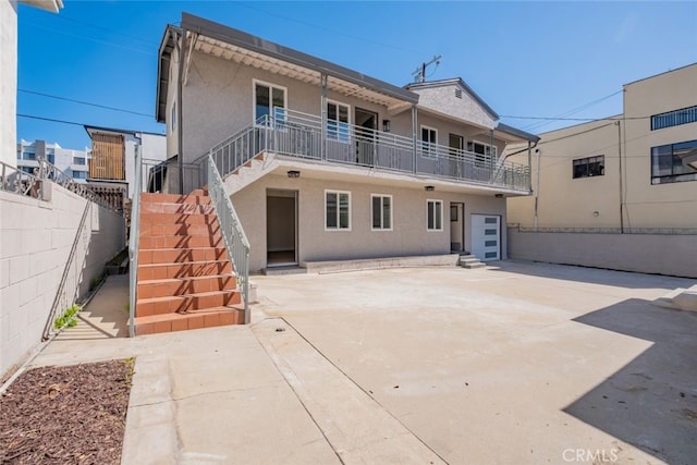 back of property with stucco siding, stairway, a patio area, fence, and driveway