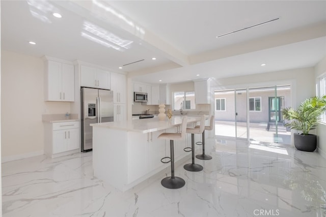 kitchen featuring a breakfast bar, white cabinetry, and stainless steel appliances