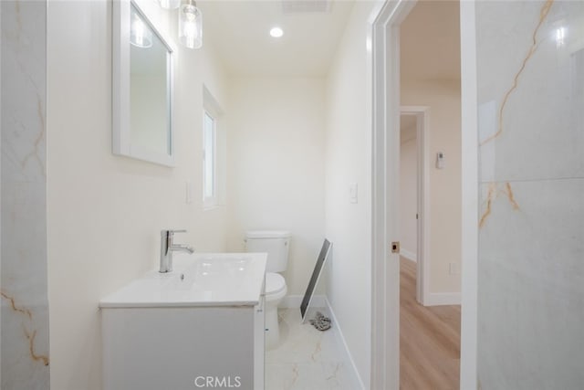 half bathroom with toilet, recessed lighting, visible vents, vanity, and baseboards