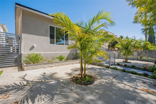 view of side of property with fence and stucco siding