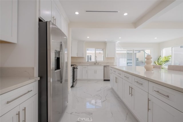 kitchen featuring marble finish floor, stainless steel appliances, white cabinetry, a sink, and recessed lighting