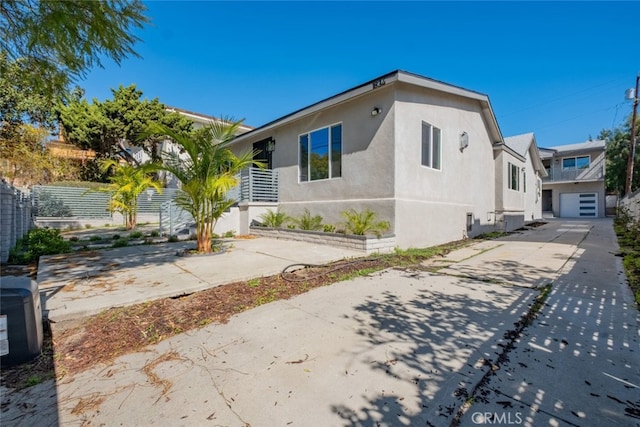 view of front facade with driveway, a garage, fence, and stucco siding