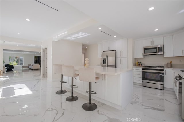 kitchen with a breakfast bar area, recessed lighting, stainless steel appliances, white cabinets, and marble finish floor