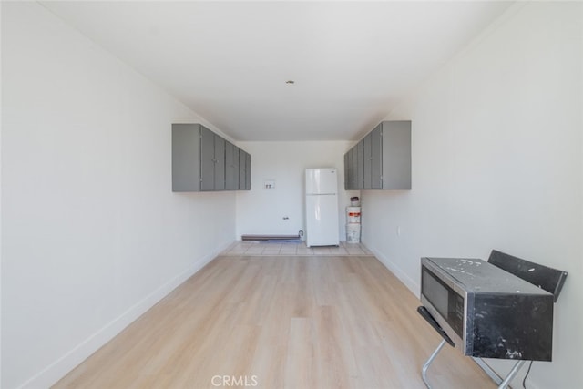 interior space featuring freestanding refrigerator and baseboards