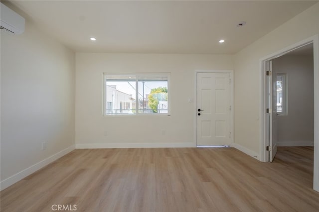 interior space with light wood-style flooring, baseboards, an AC wall unit, and recessed lighting