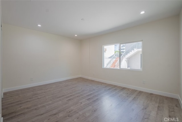 spare room with recessed lighting, light wood-style flooring, and baseboards