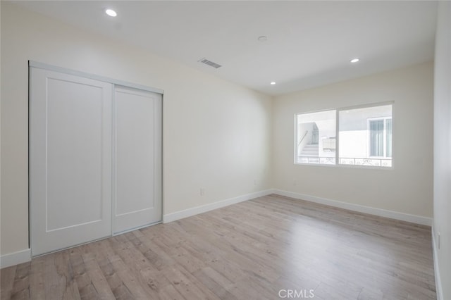 unfurnished bedroom featuring recessed lighting, a closet, visible vents, light wood-type flooring, and baseboards