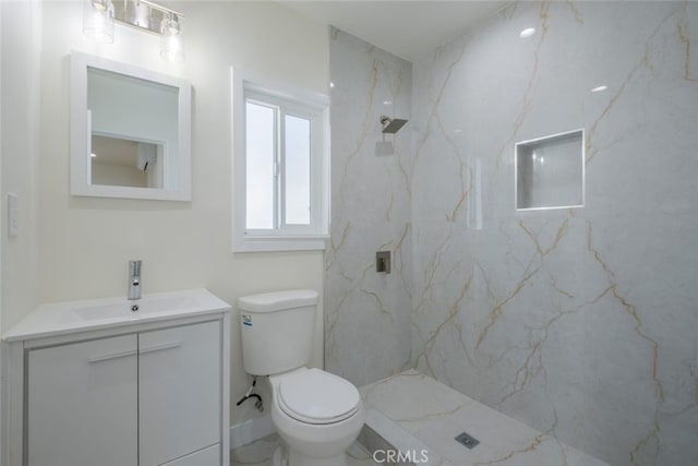 bathroom featuring toilet, a marble finish shower, and vanity