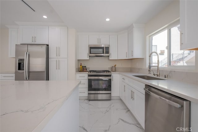 kitchen with marble finish floor, white cabinetry, appliances with stainless steel finishes, and a sink