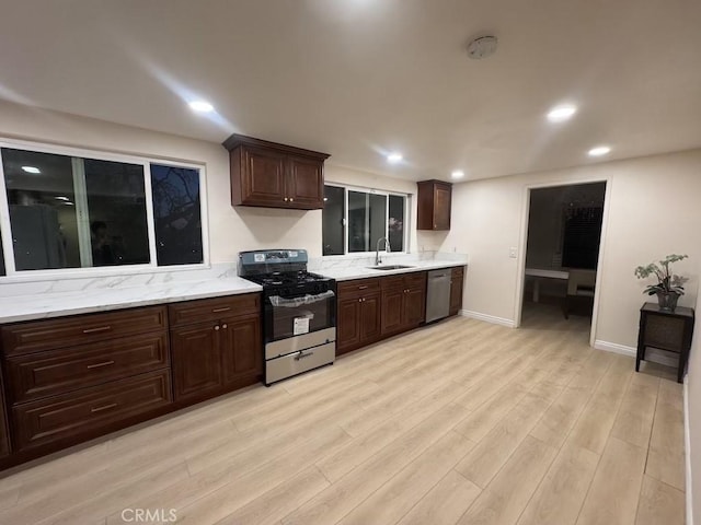 kitchen featuring recessed lighting, appliances with stainless steel finishes, light wood-style floors, a sink, and dark brown cabinets