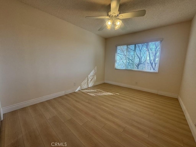 spare room featuring a ceiling fan, a textured ceiling, baseboards, and wood finished floors