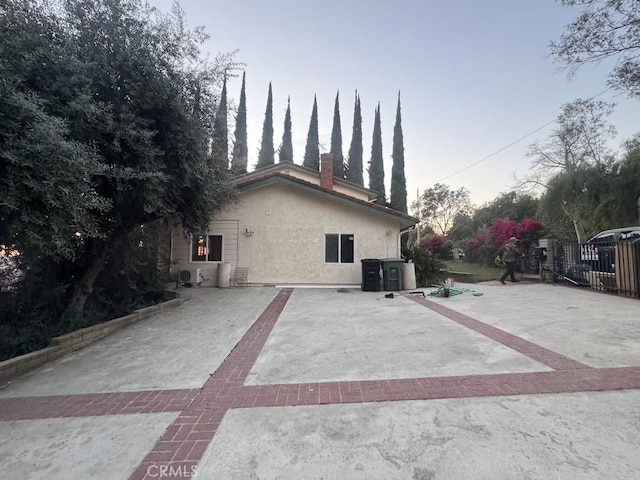 view of side of home featuring a chimney and stucco siding