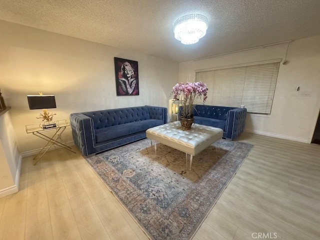 living room with a textured ceiling, baseboards, and wood finished floors