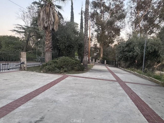 view of road featuring street lighting, concrete driveway, and a gate